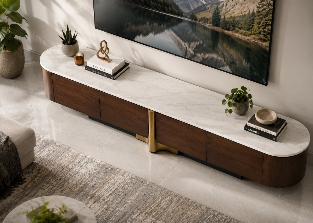 A modern curved media console with a white marble-look top and dark wood drawers, styled in a living room setting with a TV, plants, and books.