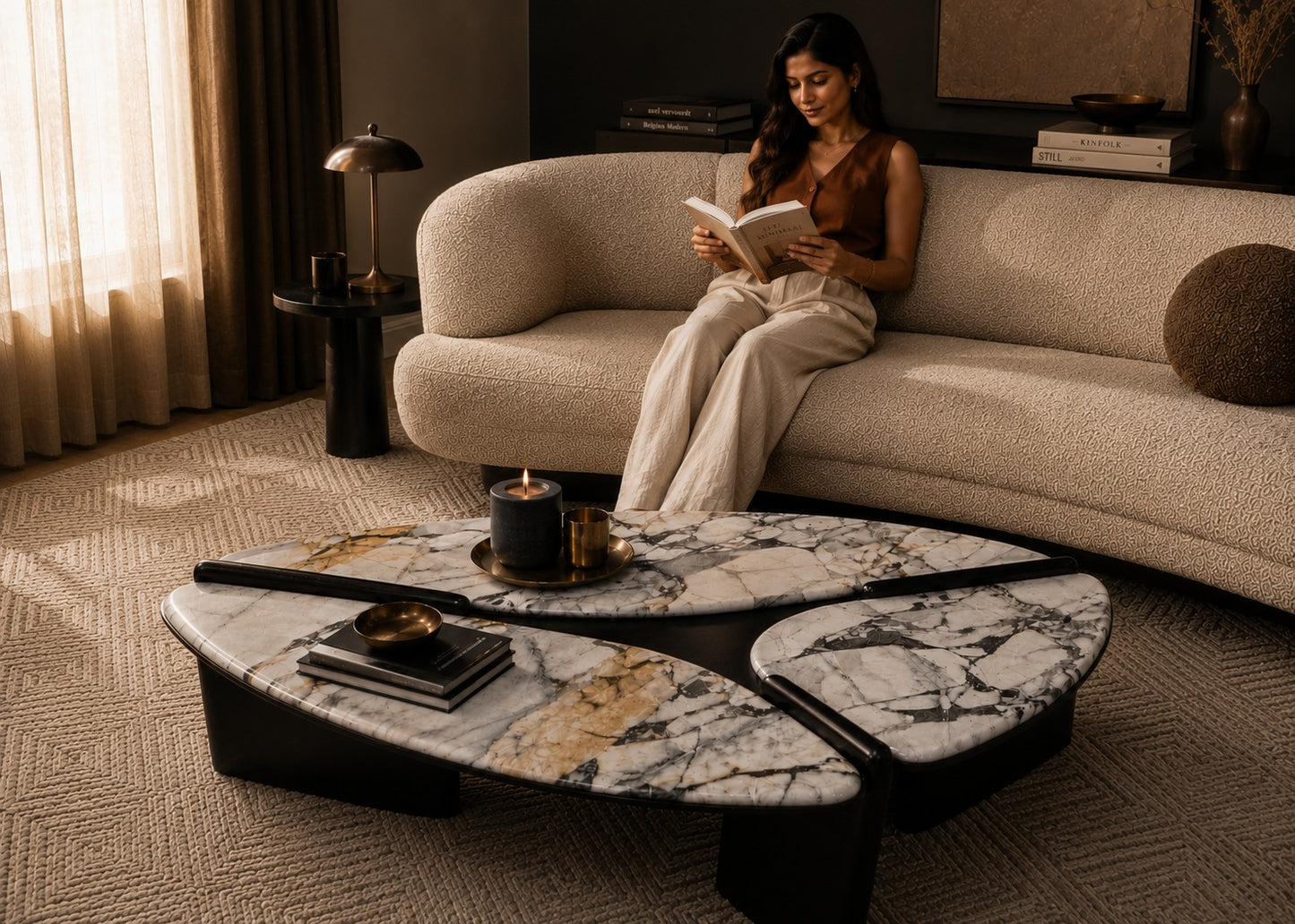 Woman reading a book on a beige sofa in a dimly lit room with a marble coffee table.