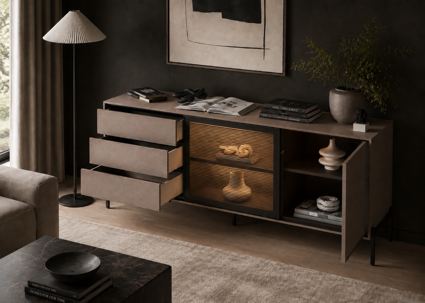A mid-century modern sideboard cabinet in a styled living room. The cabinet features a dark wood finish, three open drawers on the left, a central glass-front cabinet with warm lighting, and open shelving on the right.