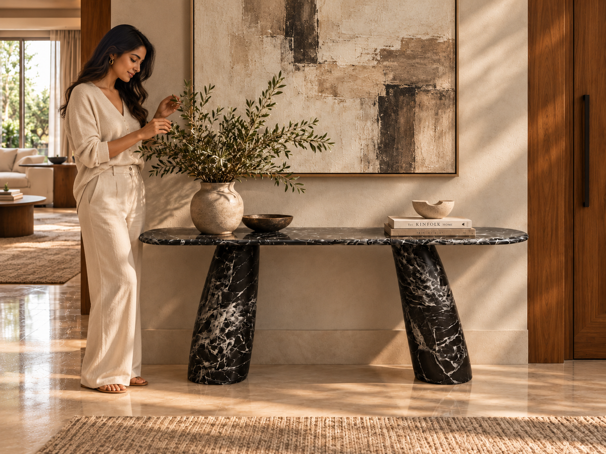 Noir Tilt sculptural marble console with elegant woman and abstract painting in modern foyer