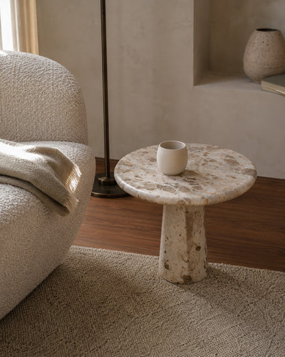 Round marble side table with a white ceramic cup in a living room setting.