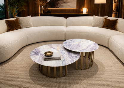 Modern living room with a curved beige sofa and marble coffee tables.