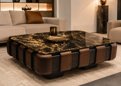 A modern square coffee table with a black and gold marbled top and brown leather-like side panels, shown in a styled living room setting.