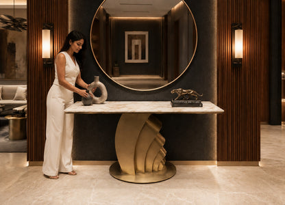 Woman in a stylish interior setting with a large mirror and decorative items.