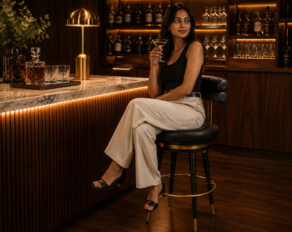 Woman sitting at a bar holding a cocktail in a dimly lit bar setting.