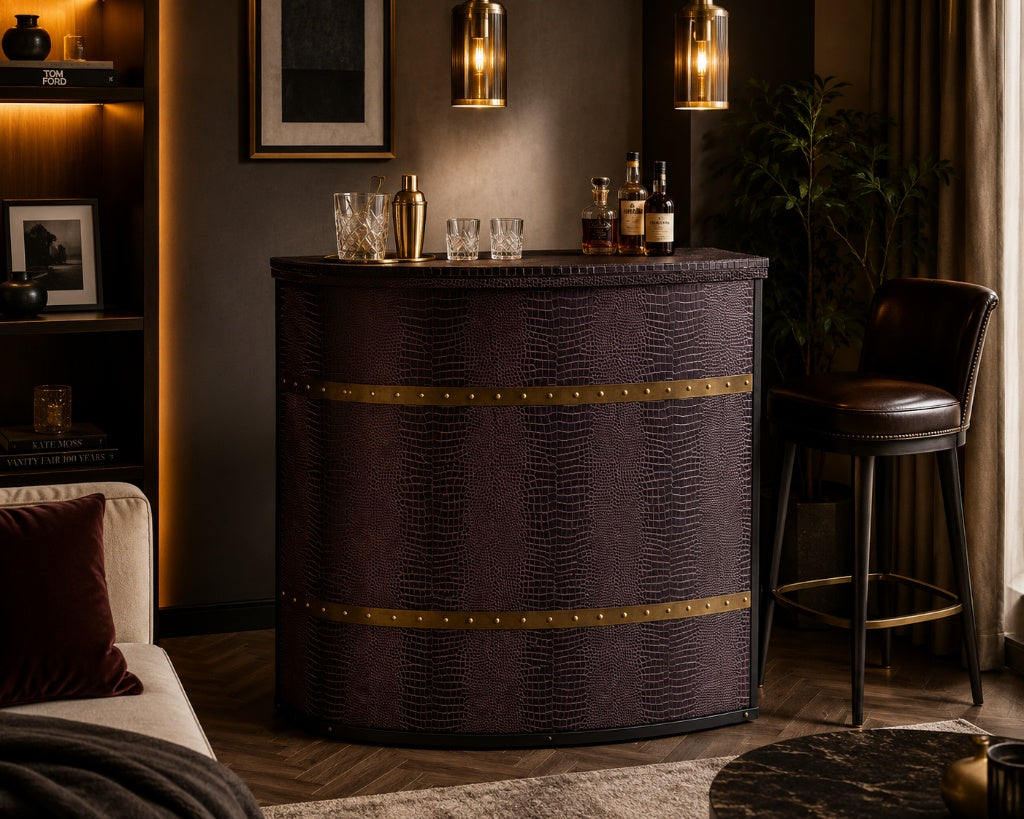 A dark purple faux-croc textured bar cabinet with brass trim, styled in a cozy, dimly lit living room next to a leather bar stool and under warm pendant lights.