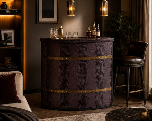 A dark purple faux-croc textured bar cabinet with brass trim, styled in a cozy, dimly lit living room next to a leather bar stool and under warm pendant lights.
