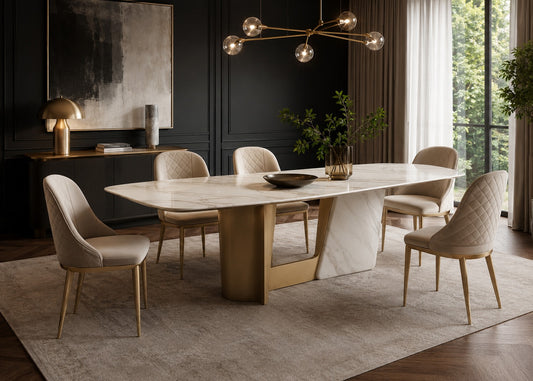 A modern dining room set featuring a rectangular white marble table with a gold metal base, surrounded by six upholstered dining chairs in beige, set on a large textured area rug in a dark, elegant room.
