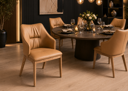 A set of modern dining chairs with tan leather upholstery and light wood legs, arranged around a round dark wood dining table in a contemporary dining room setting.