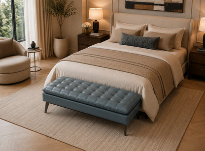Neatly made bed in a bedroom with a blue bench at the foot of the bed.