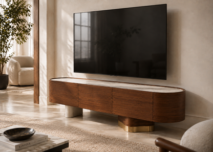 A modern curved wooden TV stand with a white marble top and gold geometric base, supporting a large black flat-screen TV against a beige wall in a styled living room.