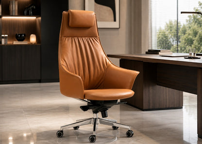A modern high-back office chair upholstered in tan leather, positioned in a contemporary office setting next to a dark wood desk.