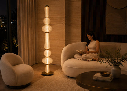 Woman reading a book on a couch in a modern living room with a tall floor lamp.