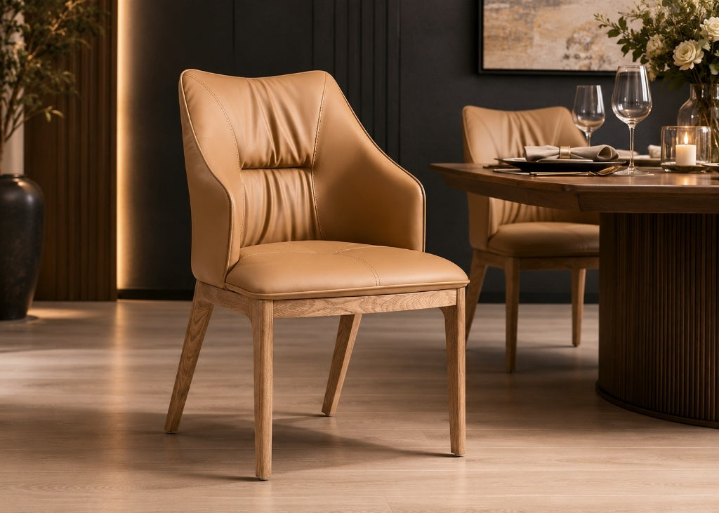 A tan leather dining chair with a light wood frame is shown in a modern dining room setting next to a matching table and another chair.