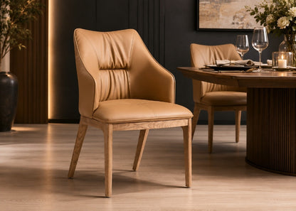A tan leather dining chair with a light wood frame is shown in a modern dining room setting next to a matching table and another chair.