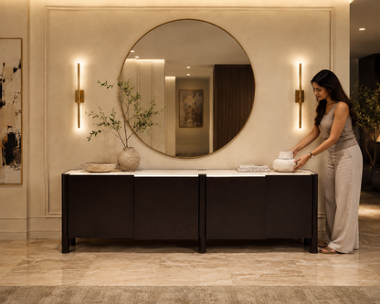Woman arranging items on a decorative console table in a stylish interior setting.