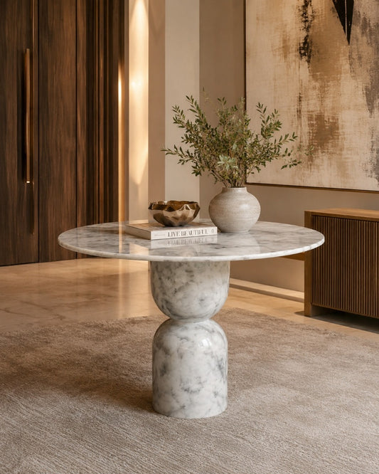 Marble side table with a vase and books in a room with wooden walls and a painting.