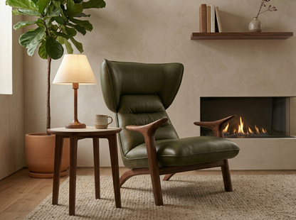 Green leather armchair in a living room with a fireplace and side table.