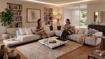Two women sitting on a beige sectional sofa in a modern living room.