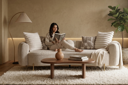 Woman reading a book on a beige sofa in a cozy living room.