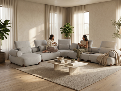 Modern living room with a large sectional sofa, coffee table, and two women sitting.