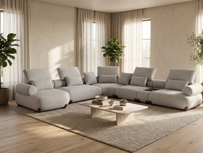 Modern living room with a large gray sectional sofa, coffee table, and decorative plants.
