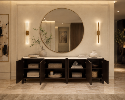 Bathroom vanity with round mirror, open cabinets, and decorative items.