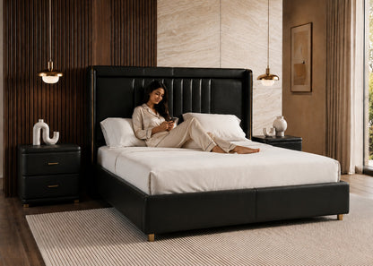 Woman lying on a black upholstered bed in a modern bedroom.