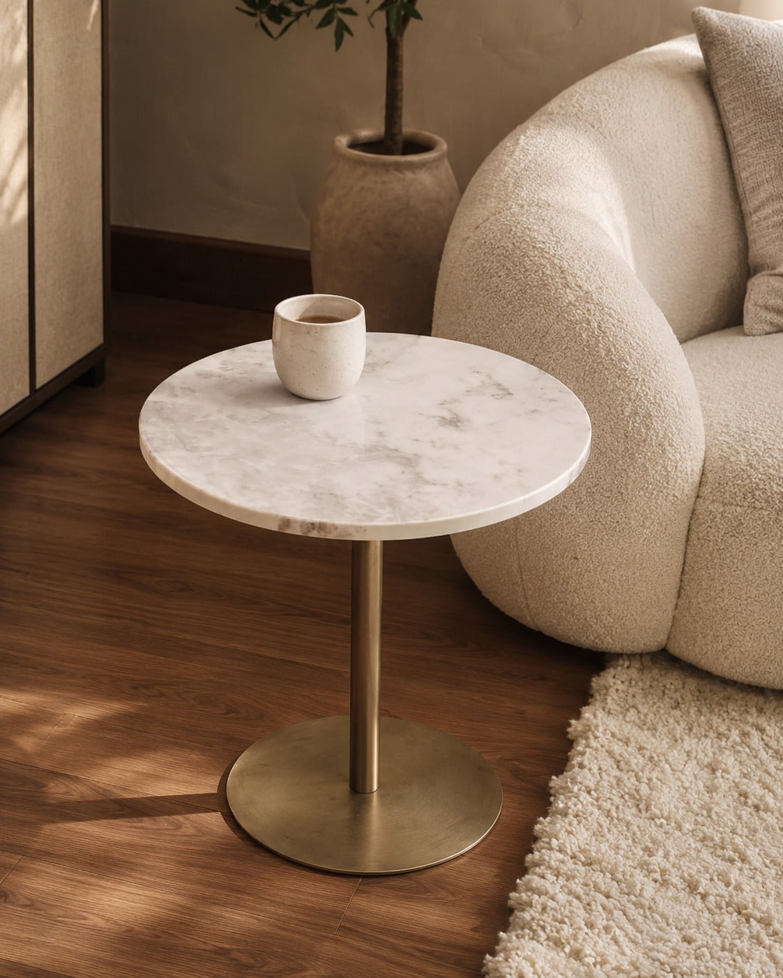 Round marble side table with brass base in a living room setting