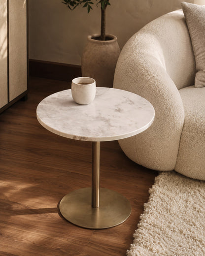 Round marble side table with brass base in a living room setting