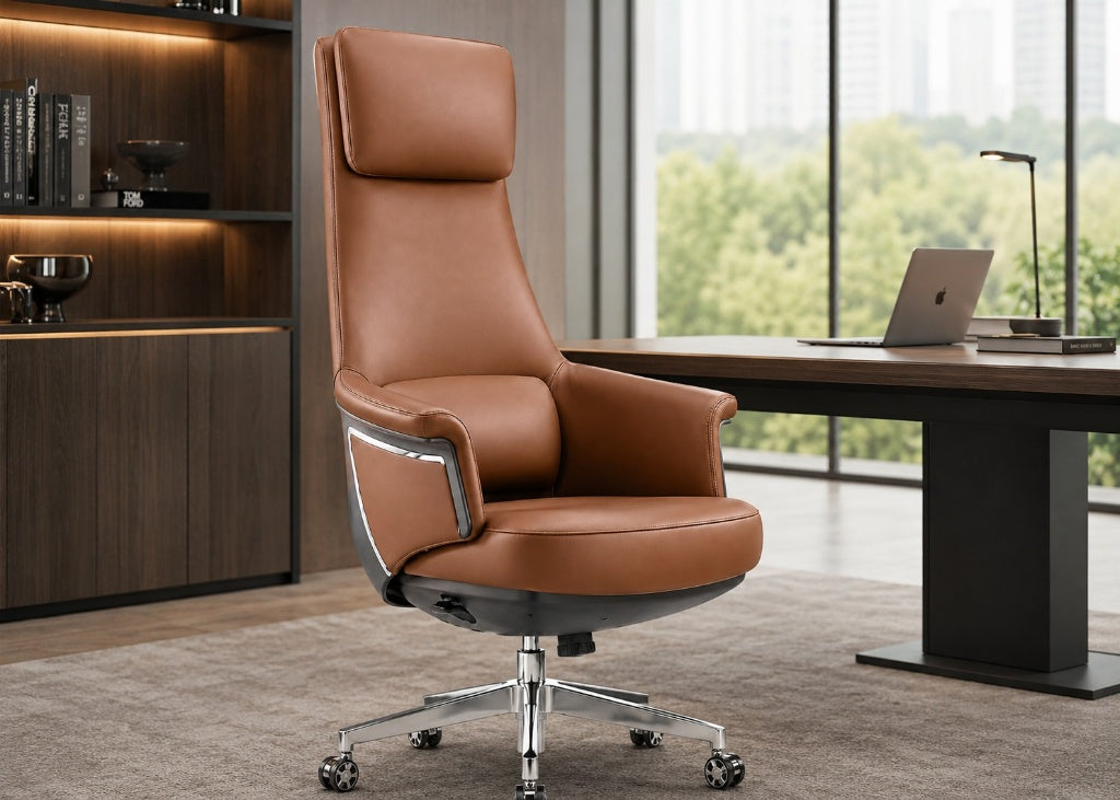A high-back brown leather office chair with a chrome five-star base, positioned in a modern office setting next to a desk and large windows.