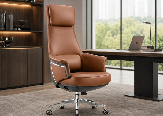 A high-back brown leather office chair with a chrome five-star base, positioned in a modern office setting next to a desk and large windows.