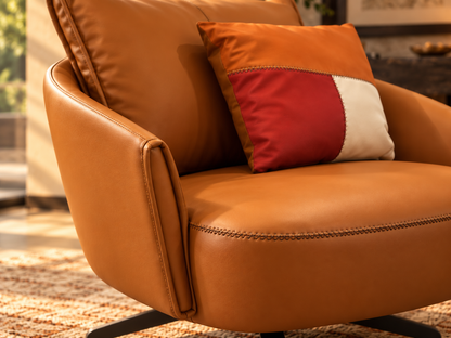 Aveline leather armchair close-up showing warm cognac colour, stitched seat edge and decorative cushion