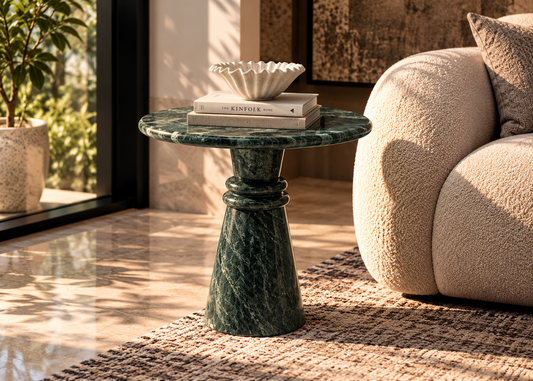 Verde Aria compact round green marble side table with flared sculptural base beside ivory boucle lounge chair in modern luxury living room