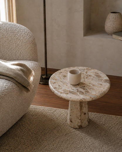 Round marble side table with a white ceramic cup in a living room setting.