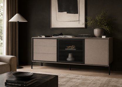 A modern sideboard cabinet in a styled living room setting. The cabinet features a light beige textured finish on the drawers and doors, with a black central door panel containing a decorative vase.
