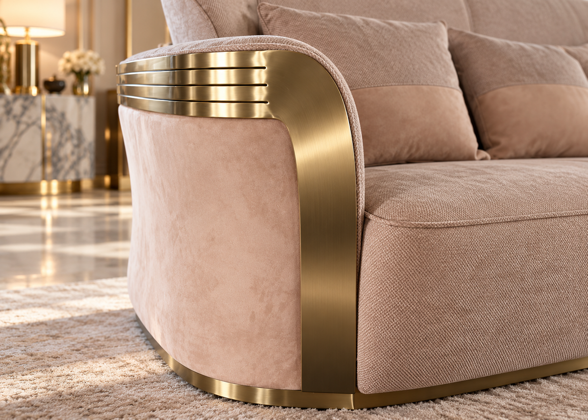 Bellara sofa close-up showing Art Deco stepped brushed champagne gold arm bands, sweeping vertical gold trim and blush suede-look panel