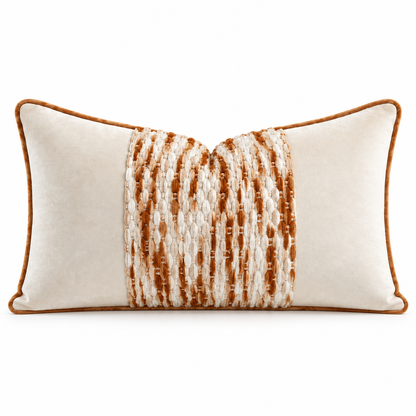 A rectangular lumbar throw pillow in cream velvet with a central vertical panel of textured woven stripes in brown and cream, finished with a warm brown piped edge.