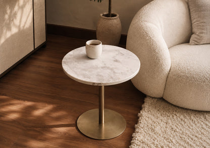 Small round marble table with a brass base in a living room setting.