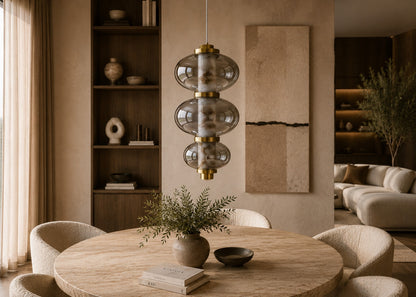 Modern living room with a round wooden table, pendant light, and bookshelf.