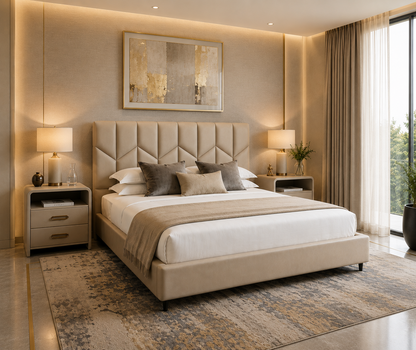 A modern bedroom featuring a beige tufted upholstered bed frame with white bedding, gray accent pillows, a patterned area rug, matching bedside tables and lamps, and a large abstract wall art piece.