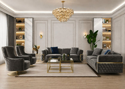 A luxury modern living room featuring a dark gray tufted velvet sofa set, two matching armchairs with gold bases, a glass and gold coffee table, and a large crystal chandelier hanging from the ceiling.