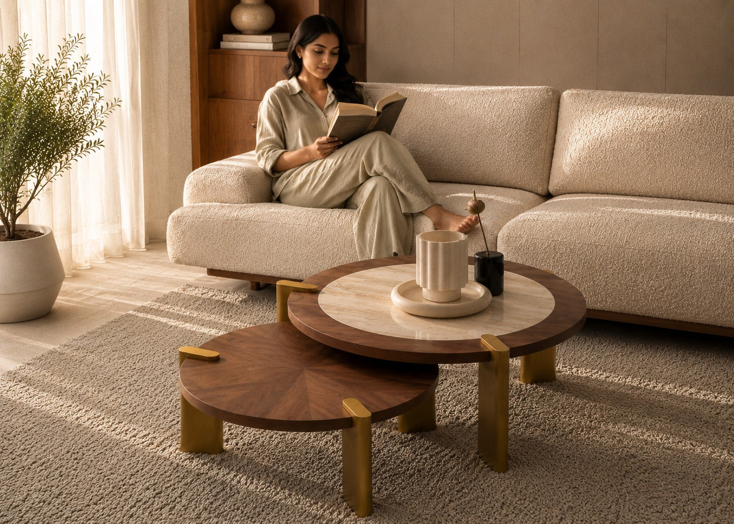 Woman reading a book on a beige sofa in a cozy living room with wooden coffee tables.