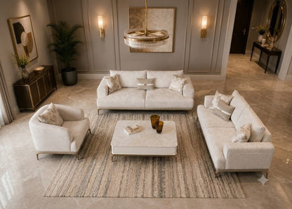 A luxury living room set featuring a cream-colored three-seater sofa, a matching two-seater armchair, and a rectangular coffee table arranged on a striped area rug in a high-end interior.