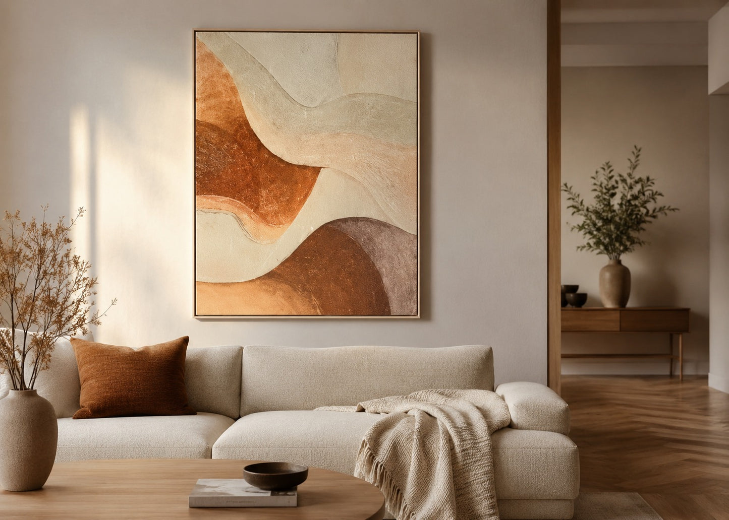 Abstract wall art with flowing organic shapes in terracotta, beige, cream, and taupe tones, displayed above a light beige sofa in a styled living room.