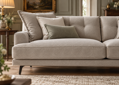 Milan sofa detailed close-up of warm greige bouclé nubby weave, gently rounded arm, tailored seat piping, channel back cushions and black blade leg