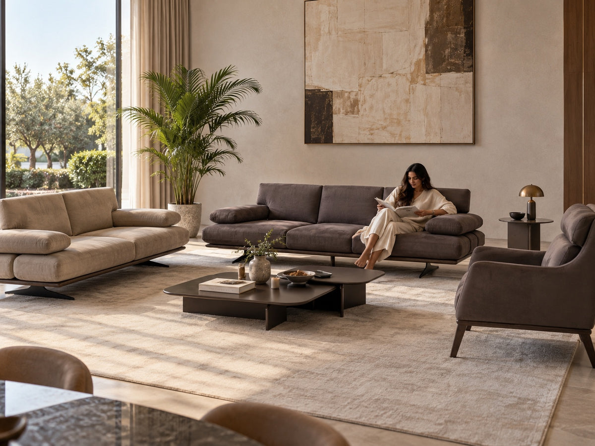 Rapid Sofa in warm taupe-grey upholstery with a woman reading in a sunlit luxury living room