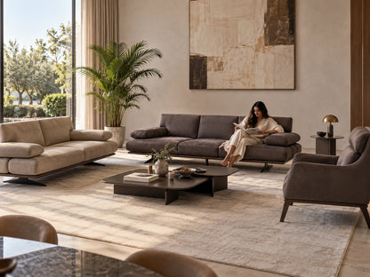 Rapid Sofa in warm taupe-grey upholstery with a woman reading in a sunlit luxury living room