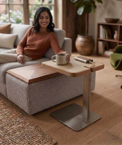 Woman sitting on a sofa with a coffee cup, next to a adjustable table in a cozy living room.