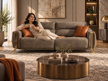 Taj Sofa with a modern Indian woman lounging comfortably on the quilted olive taupe sofa